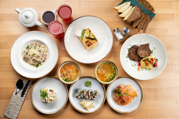 Continental lunch on light wooden table, variety of meals on a table top view