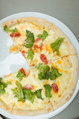 pizza with lettuce and tomato slices on a white plate, five slices of pizza on a white round plate, vegetarian pizza without one slice on a plate