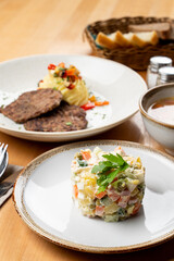 Russian lunch with roasted meat patties, soup and vegetable salad on wooden table side view