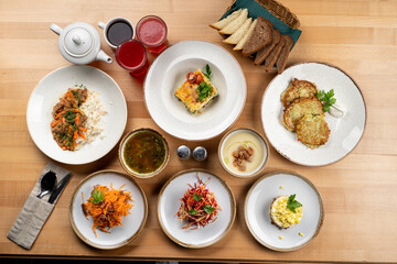 Typical russian restaurant lunch menu, different meals in white plates, shot directly above a wooden table
