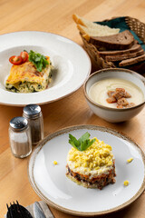 Beef lasagna, mushroom cream soup and layered fish salad as a lunch in a cafe, side view