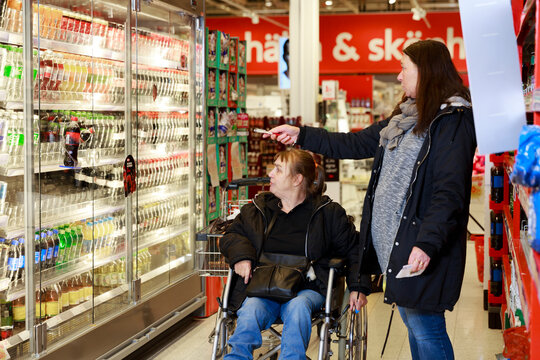 Female carer helping woman with shopping, Sweden