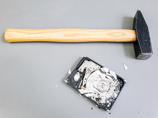 Shattered platter in computer hard drive disk and a hammer.