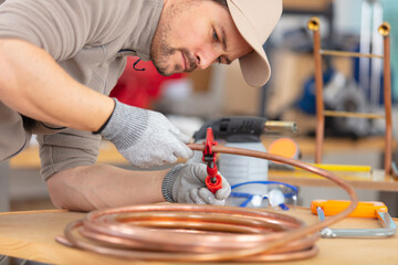 plumber cutting a copper pipe with a pipe cutter
