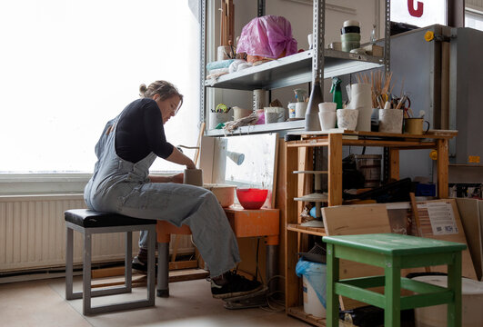Woman preparing clay in workshop, Sweden