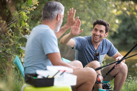 Two Fishermen Making A High Five Gesture