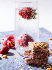 Healthy sweet dessert snack. Cereal granola bar with nuts and strawberries on a light blue background. - 394470104