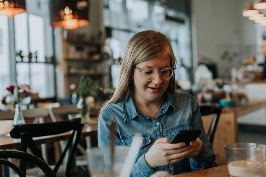Smiling girl using phone at table, Sweden