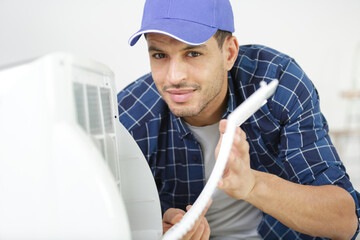 a professional electrician man is fixing the heavy air conditioner