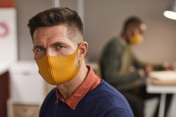 Close up portrait of handsome mature man wearing mask and looking at camera while working in office, copy space