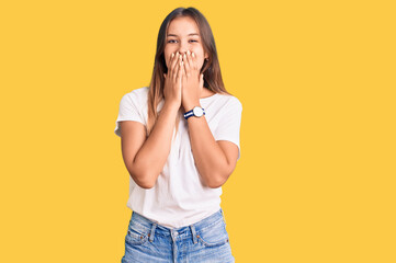 Beautiful caucasian woman wearing casual white tshirt laughing and embarrassed giggle covering mouth with hands, gossip and scandal concept