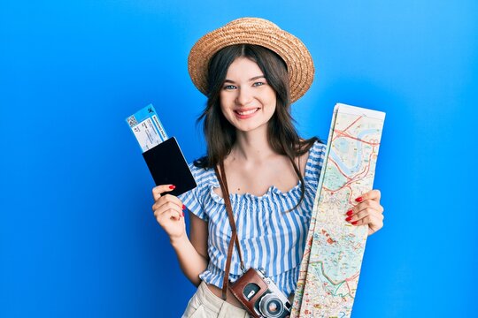 Young beautiful caucasian girl holding passport and city map smiling with a happy and cool smile on face. showing teeth.