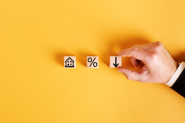 symbols house, percent and down arrow on wooden cubes and orange background. concept of low cost...