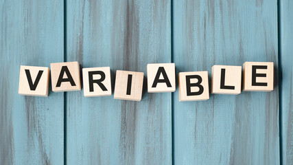 the word variable wooden cubes with burnt letters, variable life, gray background top view.