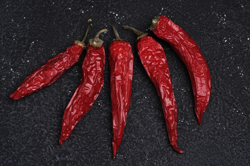 red hot dried chili peppers on a black concrete textured table