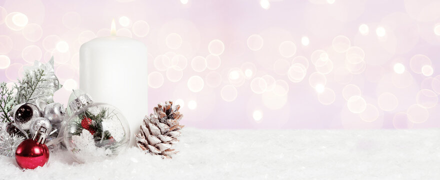 christmas candle with ornament, bells and pine cone.
Pink snowy background of xmas decoration. 