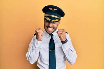 Handsome hispanic man wearing airplane pilot uniform excited for success with arms raised and eyes closed celebrating victory smiling. winner concept.