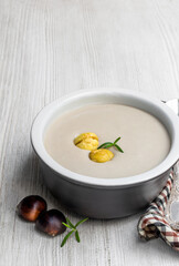 Chestnut cream soup in wooden bowl on white wooden table