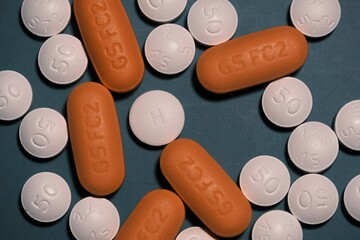 white and orange antiretroviral therapy pills for the treatment of HIV on a tidewater green trendy...
