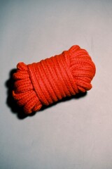 Fototapeta na wymiar red fabric rope for shibari on the gray background. jute fetish accessories. horizontal image. Concept of sadomasochism.