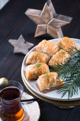 Traditional Turkish baklava in white plate on wooden background, east Mediterranean cuisine, Christmas or New year decoration