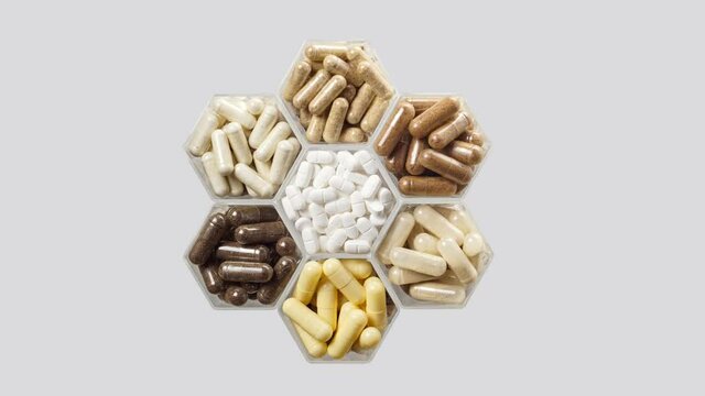 Various pills and capsules in hexagonal jars appear on a grey background