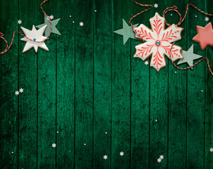 Festive decoration on green wooden background. Snowflake shaped gingerbread cookie.	