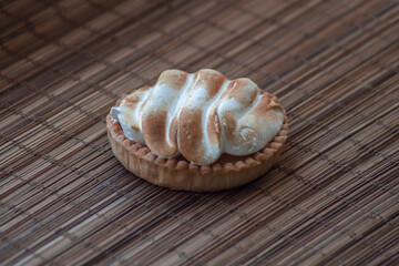 Traditional french lemon tart with meringue on the top on the bamboo background. Delicious breakfast desert pâtisserie. 