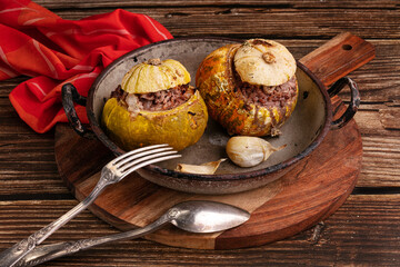 Giraumon or turbaned pumpkin stuffed with meat in an old dish on a wooden table