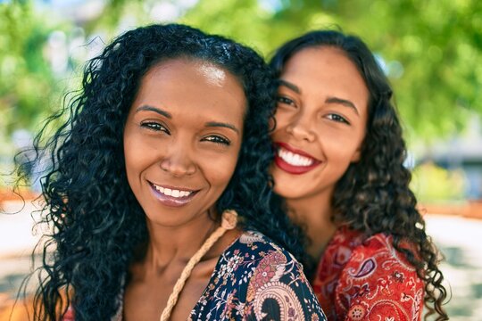 African american mother and daughter smiling happy hugging at the park.