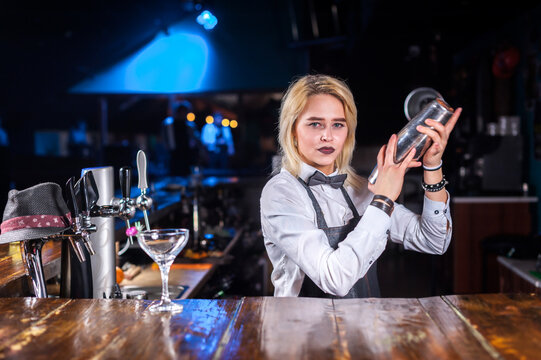 Girl bartender mixes a cocktail on the public house