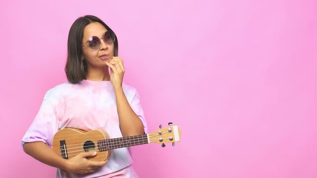 Young latin woman playing ukelele looking sideways with doubtful and skeptical expression