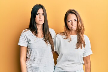 Hispanic family of mother and daughter wearing casual white tshirt skeptic and nervous, frowning upset because of problem. negative person.