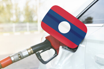 Flag of Laos on the car's fuel filler flap with gas pump nozzle in the tank.