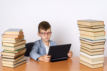 The student does homework using a tablet. He has books on both sides.