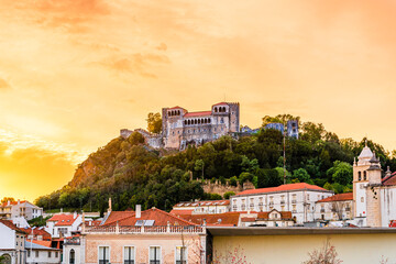The castle of Leiria on the top of a hill surroundedn by trees beyound buildings in Leiria, Portugal - 394480149
