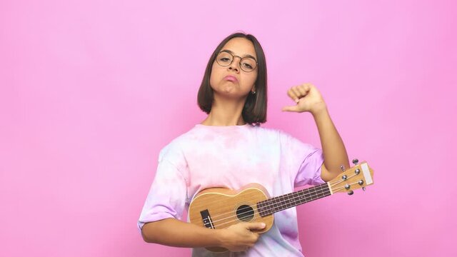Young latin woman playing ukelele feels proud and self confident, example to follow