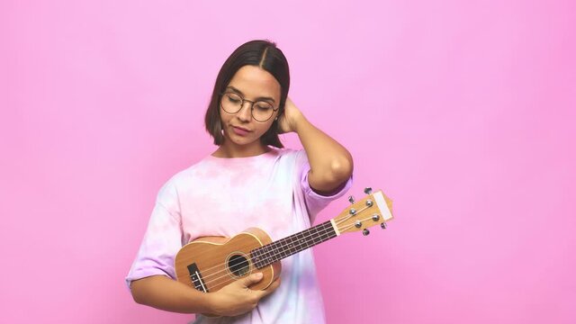 Young latin woman playing ukelele being shocked, she has remembered important meeting