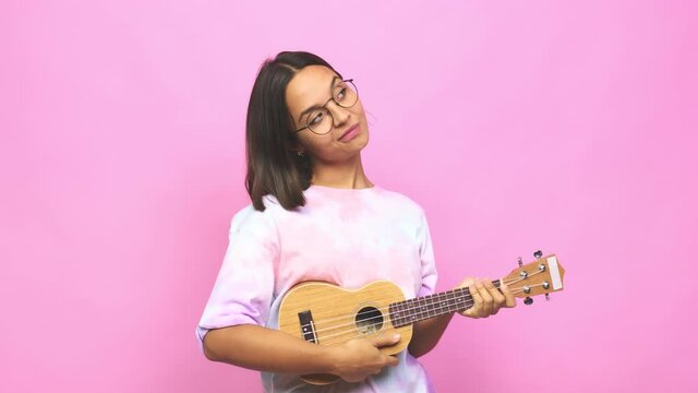 Young latin woman playing ukelele dreaming of achieving goals and purposes