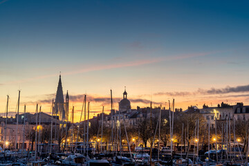 View of the old harbor of La Rochelle at blue hour with church, clock and matt boats