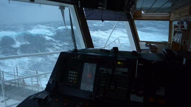 View from the bridge of the ship on the big waves. The ship is rocking hard. Storm at sea. A strong wind rips the foam from the crest of the wave. View from the window of the ship's chart room.