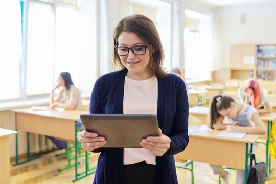 Portrait of mature woman teacher in classroom with digital tablet