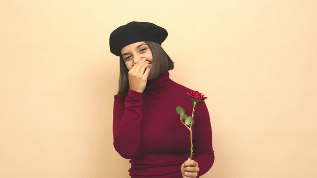 Young latin woman with boina holding rose having an idea, inspiration concept
