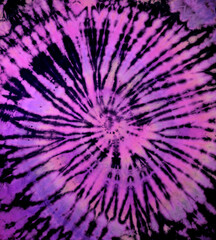 Spiral tie dye texture. Reverse swirl tiedye pattern. Tie-dye background in purple pink.