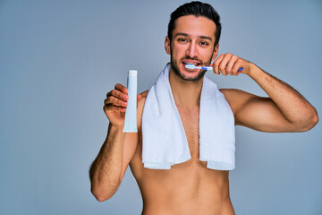 Guy with smile with black hair with a beard brushes his teeth shows a toothpaste . Dental concept