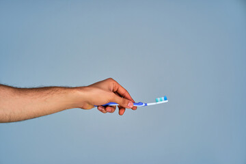 Closeup tanned male hand with a toothbrush. Dental concept