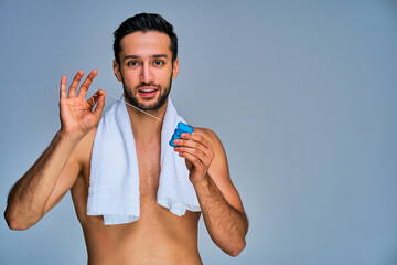 Guy with smile with black hair with a beard shows a blue box of dental floss on hands. Dental concept