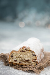 Christstollen, traditonal christmas cake with nuts, raisons, marzipan on a blue background, empty space for text