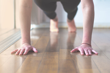 Woman doing plank exercise or push ups at home, selective focus