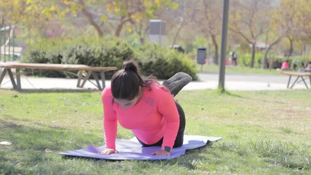 Mujer hermosa hace una secuencia de ejercicios en el parque en una tarde de verano 